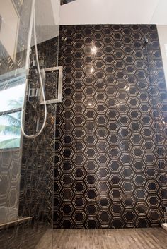 a bathroom with black and white tiles on the wall, shower head, and wooden flooring