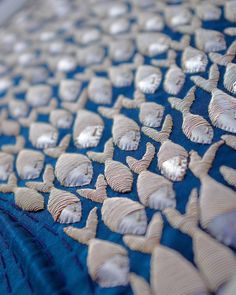 an intricately designed piece of cloth with white shells on blue fabric, closeup