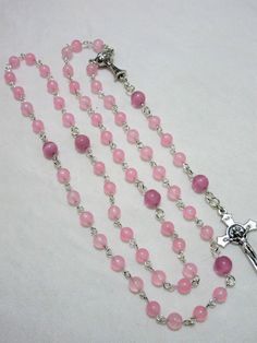 This pink First Communion rosary for girls is made with 6mm pale pink agate rounds and 8mm matte pink cat's eye beads. It measures about 27 inches around the body and has a 5 inch cross drop. The crucifix and the chalice are Italian made oxidized silver. I hand turned the silver plated wires. This rosary will be slipped into a velvet bag and shipped in a bubble mailer. Pink Rosary With 8mm Round Beads, Catholic Communion, Catholic Rosary, Matte Pink, Rosary Catholic, Pink Agate, Eye Beads, Bubble Mailer, Pink Cat