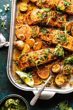 a pan filled with chicken and vegetables on top of a blue table next to utensils