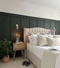 a bedroom with green walls and white bedding has a candle on the end table