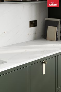 a white counter top sitting next to a sink under a shelf with books on it