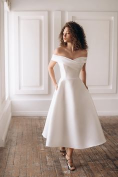 a woman in a white dress posing for the camera with her hands on her hips