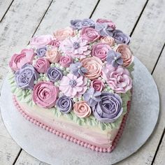 there is a heart shaped cake with flowers on the top and bottom, decorated in pastel colors