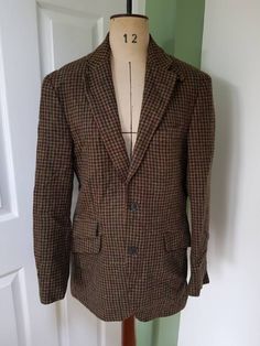 Stylish MARKS & SPENCER men's jacket in a houndstooth Moon Yorkshire Tweed. Single-breasted style; two external pockets (plus one dummy pocket), three internal. Lined in gorgeous purple satin (body) and white and purple striped satin (sleeves). Mottled brown buttons.  The tweed blends green, plum and blue tones on a brown base. The jacket can be worn in a classic blazer style or the collar can be buttoned up. This looks like a modern size Medium. Measurements are as follows: Shoulder to hem:  30 Long Sleeve Tweed Sport Coat, Business Casual Tweed Sport Coat With Pockets, Brown Houndstooth Tweed Jacket For Winter, Winter Brown Houndstooth Tweed Jacket, Winter Plaid Sport Coat With Welt Pockets, Plaid Tweed Blazer With Pockets, Winter Plaid Tweed Jacket With Welt Pockets, Fall Tweed Sport Coat With Welt Pockets, Fitted Tweed Sport Coat With Houndstooth Pattern