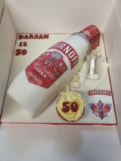 a birthday cake in the shape of a bottle and cupcakes with frosting