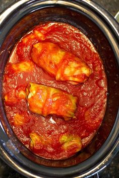 two pieces of meat covered in marinara sauce in the slow cooker, ready to be cooked