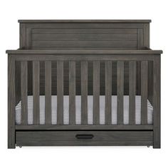 a wooden crib with two drawers and a mattress in the bottom drawer, against a white background