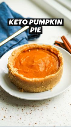 a white plate topped with a pie on top of a table next to cinnamon sticks