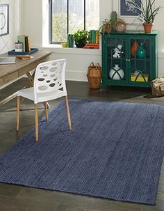 a room with a table, chair and rug on the floor in front of a window