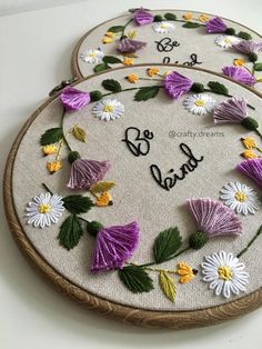 two embroidered hoops with flowers and the words be kind written on them