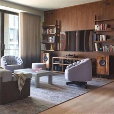 a living room filled with lots of furniture and bookshelves next to a window