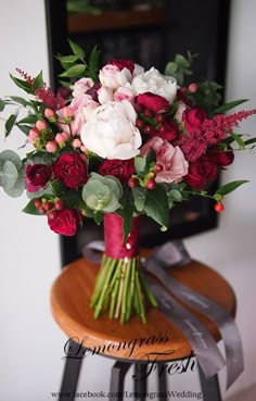 a bouquet of red and white flowers sitting on top of a wooden table