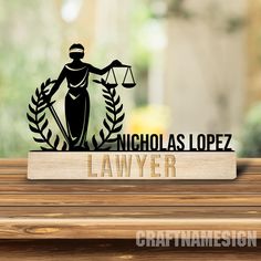 a wooden table topped with a sign that says nicholas lopez lawyer and an image of a lady justice figure