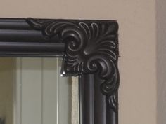 an ornate black framed mirror hanging on the wall