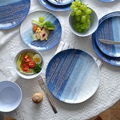 a table topped with blue plates and bowls filled with food next to utensils