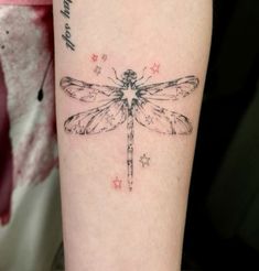 a small dragonfly tattoo on the right arm and left leg, with stars around it