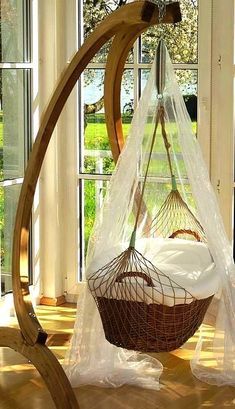 a hammock hanging from a wooden frame in front of a window with curtains