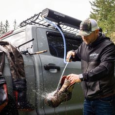 a man is washing his feet with water from a hose in the back of a truck