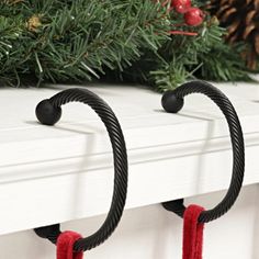 two christmas decorations hanging from the side of a white mantle with pine cones on top