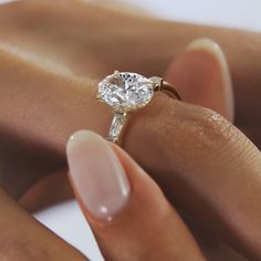 a woman's hand holding an engagement ring with a diamond on it and the band around her finger