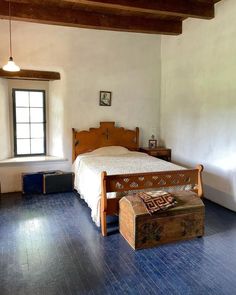 a bedroom with a bed, dresser and chest in it's center area next to a window