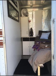 a bed sitting inside of a bedroom next to a white wall and door with a black rug on the floor