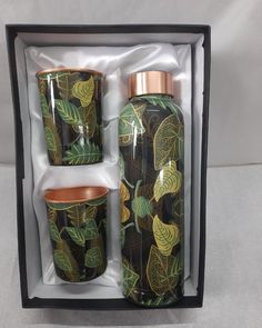 two green and gold vases in a black box