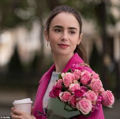 a woman in a pink coat holding a bouquet of roses and a cup of coffee