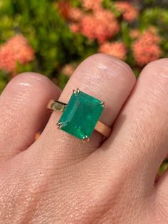 a woman's hand with a ring on it and an emerald stone in the middle