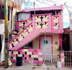 a pink and white house with swans painted on it's front porch, next to a gate