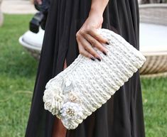 a woman in a black dress holding a white purse