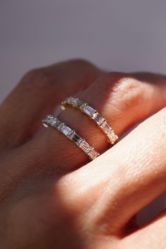 a woman's hand with two gold rings on it and one diamond ring in the middle