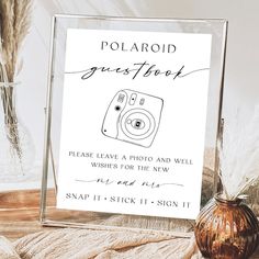 a polaroid guest sign sitting on top of a table next to a glass vase