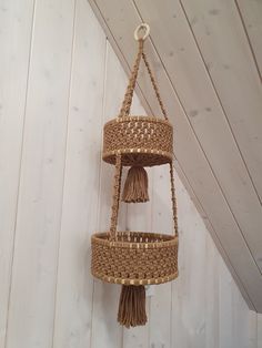 a hanging basket with tassels on the side of a white wooden wall in an attic