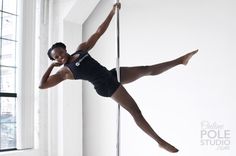 a woman in black leotard and tights is doing pole dancing on a pole