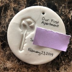 a purple piece of paper on top of a white button with the words our first apartment written on it