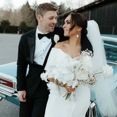 a bride and groom standing in front of a car