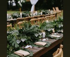 a long table with place settings and greenery