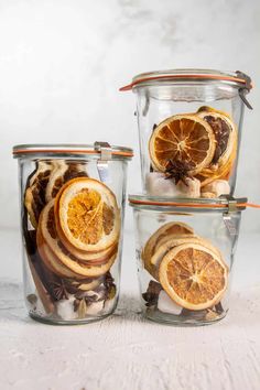 three glass containers filled with sliced oranges and spices