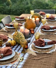 the table is set with plates, candles and napkins for thanksgiving dinner guests to enjoy