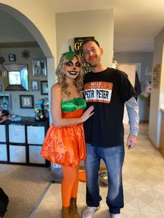 a man standing next to a woman dressed as a pumpkin and holding a sign that says fair peter