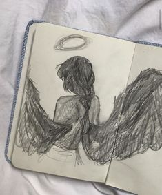 an open notebook with a drawing of two angel's wings on top of it