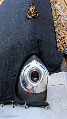 an open umbrella sitting on the ground next to a wall with gold and black designs