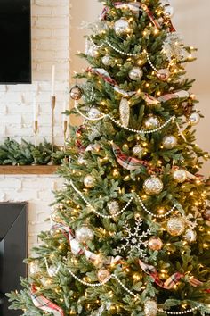 a decorated christmas tree in front of a fireplace