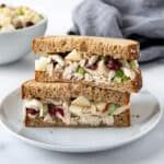 a sandwich cut in half sitting on top of a white plate next to a bowl of salad