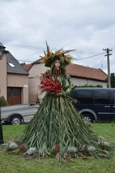 a woman is dressed up in grass and flowers