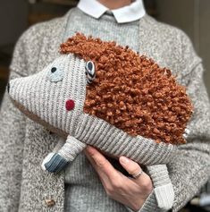 a woman holding a knitted hedge pillow