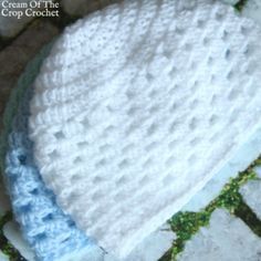 a crocheted white and blue hat sitting on top of a tile floor next to a brick wall