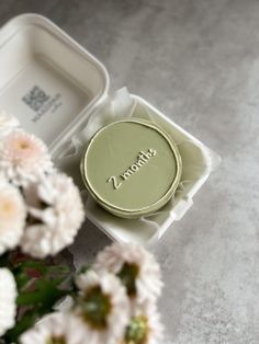 an empty box with some flowers in front of it on a table next to a flower vase